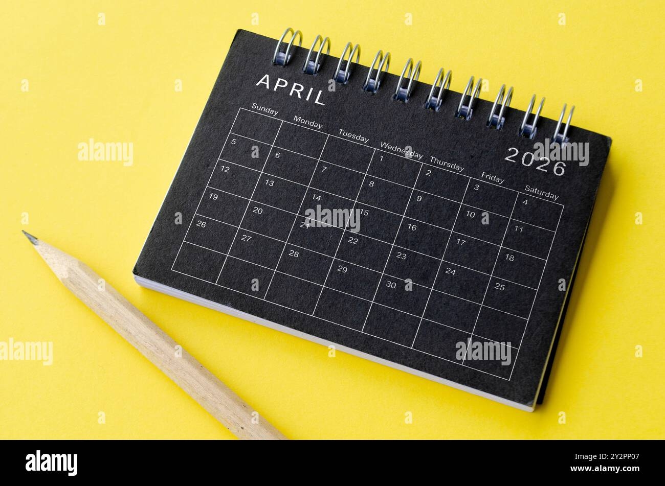 Top View Of April 2026 Calendar On Black Notepad With Yellow 